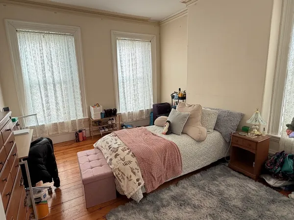 a bedroom with a bed a couch and a dresser next to a window