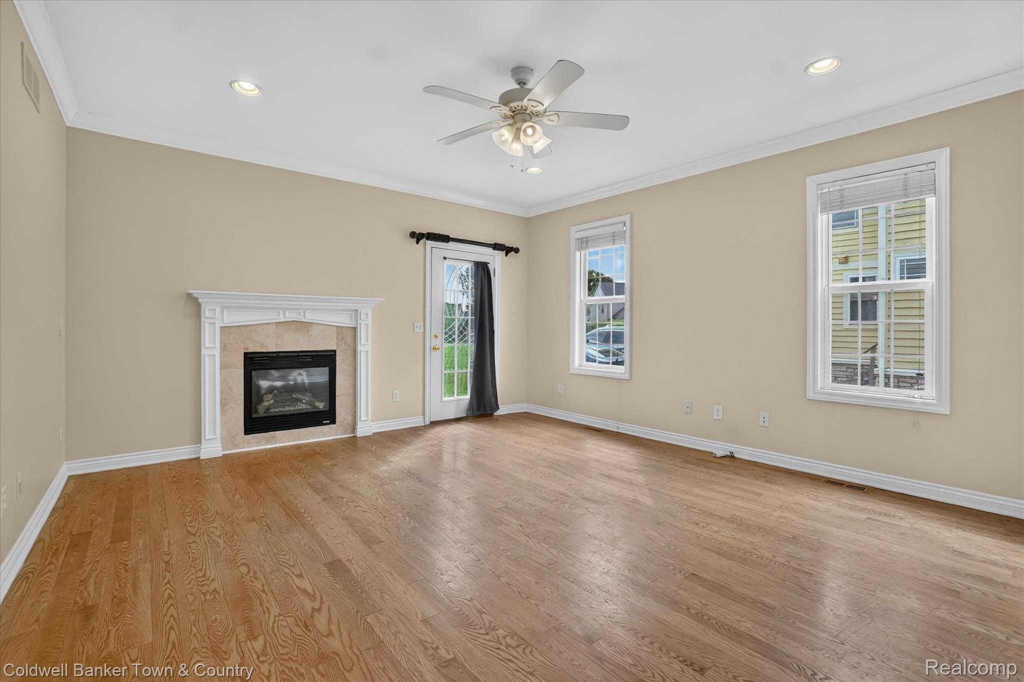 1725 Town Commons Drive Howell, MI 48855 - Photo 24 of 53 Spacious room featuring wood-finish flooring, a decorative fireplace with a tile surround and white mantel, and crown molding