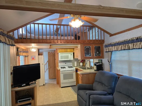 a living room with furniture a flat screen tv and a kitchen view