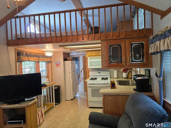 a living room with furniture a flat screen tv and a refrigerator