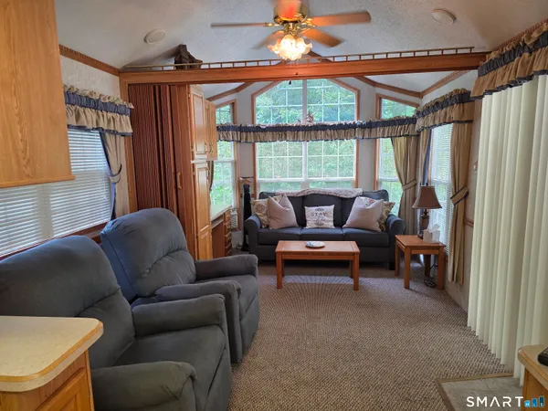 a living room with furniture a kitchen island with large windows