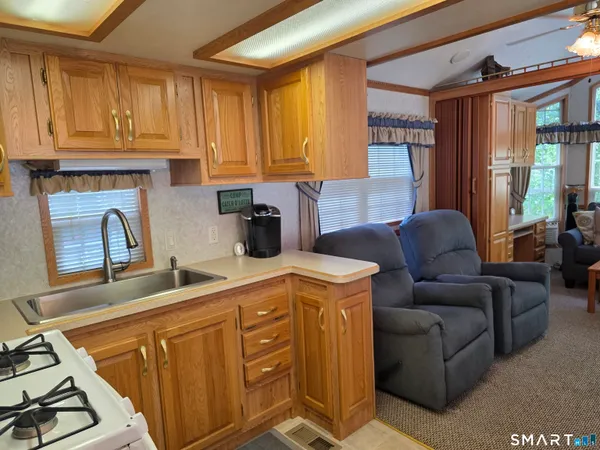 a living room with furniture a flat screen tv and kitchen view