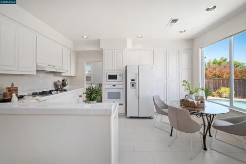 a kitchen with stainless steel appliances a dining table chairs refrigerator and sink