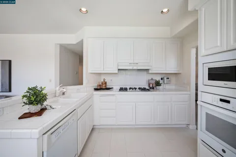 a kitchen with granite countertop white cabinets and white appliances