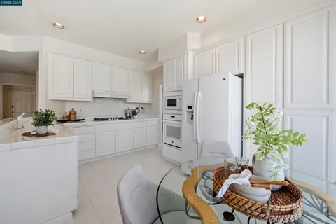 a kitchen with stainless steel appliances a white table chairs and a refrigerator