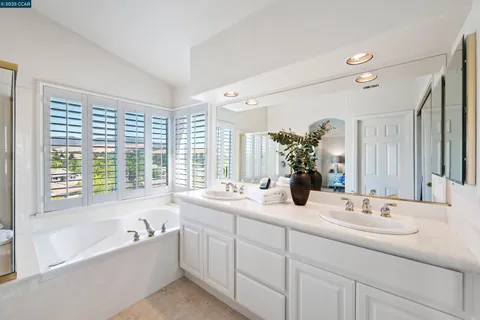 a bathroom with a bathtub a double vanity sink and mirror