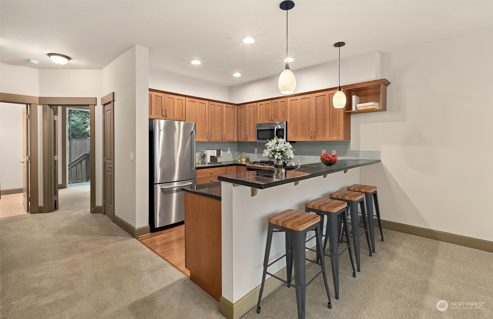2115 201st Place Southeast, Unit I4 Bothell, WA 98012 - Photo 3 of 24 a kitchen with stainless steel appliances kitchen island granite countertop a refrigerator a stove a sink a dining table and chairs with wooden floor