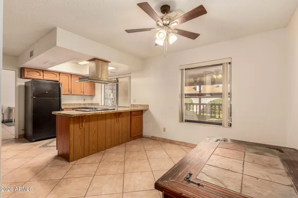 a kitchen with stainless steel appliances kitchen island granite countertop a refrigerator a sink a stove top oven and a dining table