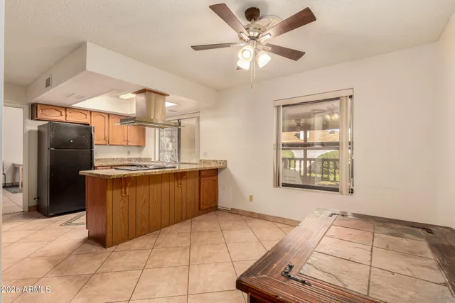 a kitchen with stainless steel appliances kitchen island granite countertop a refrigerator a sink a stove top oven and a dining table