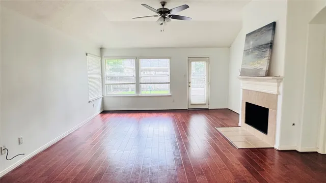 an empty room with windows fireplace and wooden floor