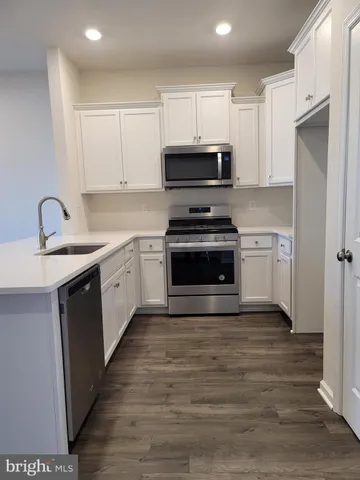 a large white kitchen with kitchen island a sink wooden floor and a stove