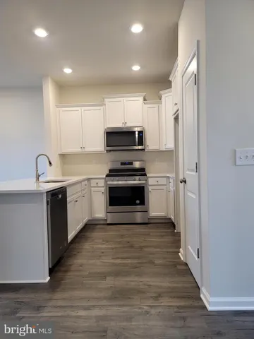 a kitchen with cabinets stainless steel appliances a sink and wooden floor