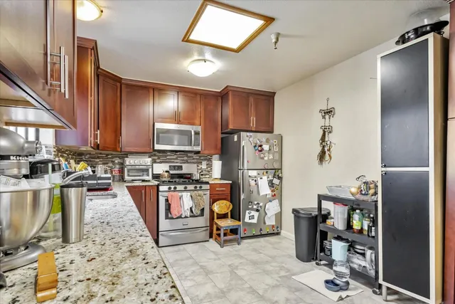 a living room with furniture a flat screen tv and a refrigerator