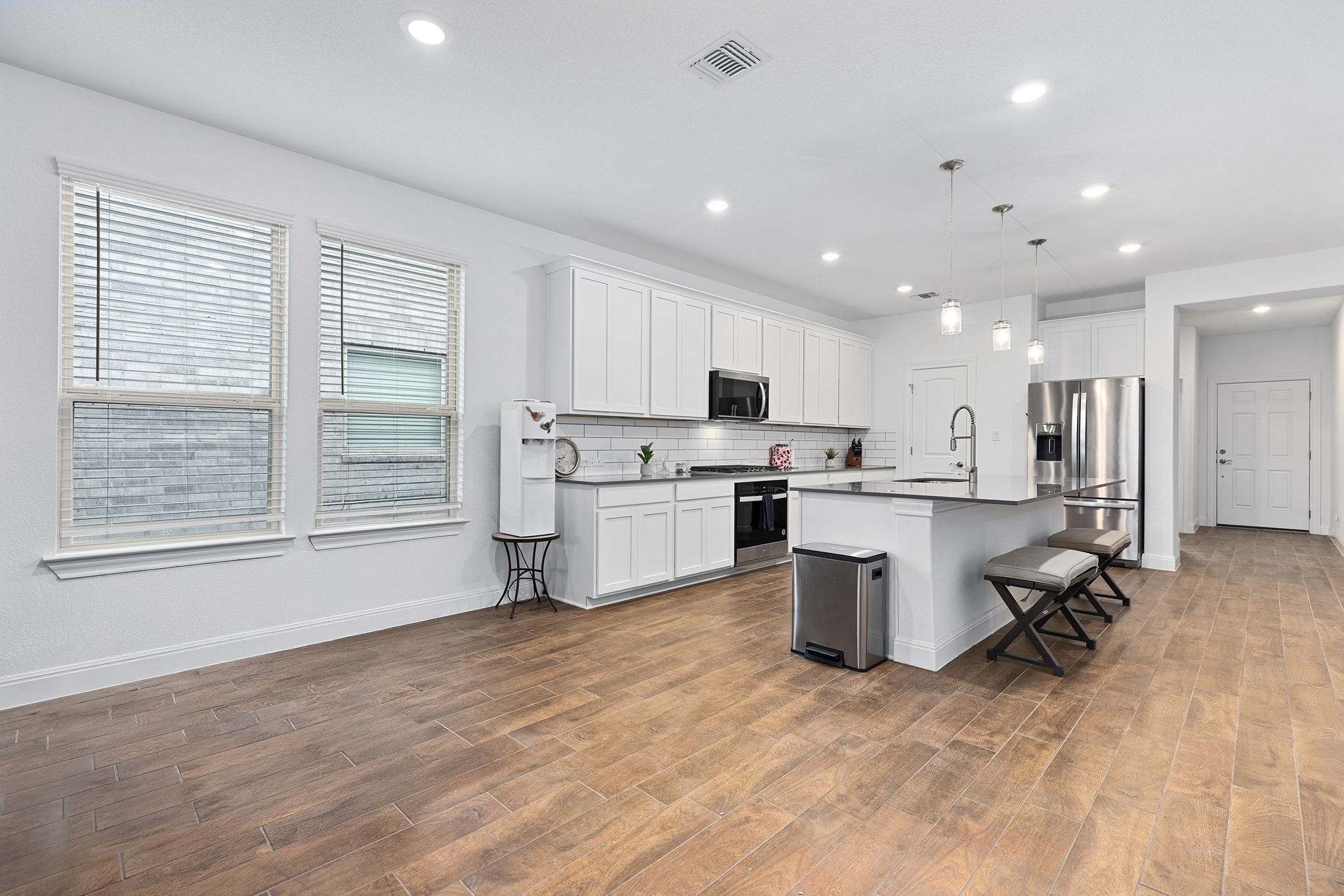116 Raleigh Drive Georgetown, TX 78633 - Photo 8 of 28 A well-lit, open-concept kitchen and living area showcases rich wood-look flooring and a modern aesthetic.