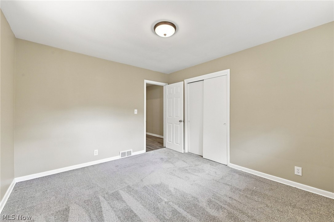 558 Garnette Road Akron, OH 44313 - Photo 23 of 31 Spacious bedroom featuring neutral painted walls, carpeted flooring, white trim, and a flush-mount ceiling light