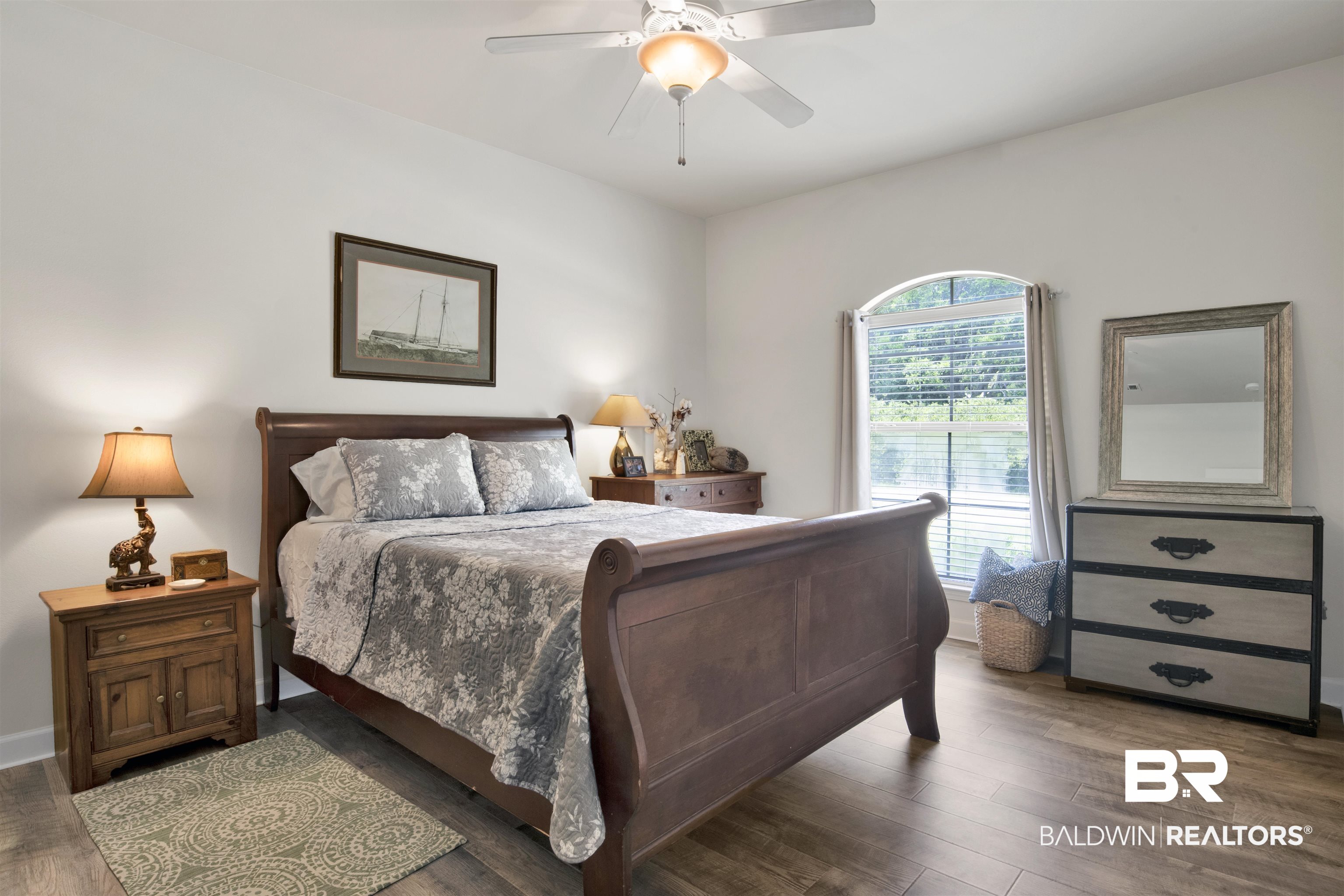 10368 Gayfer Rd Extension Fairhope, AL 36532 - Photo 25 of 43 Spacious bedroom featuring light-toned walls, wood-finish flooring, an arched window, and a ceiling fan with integrated lighting