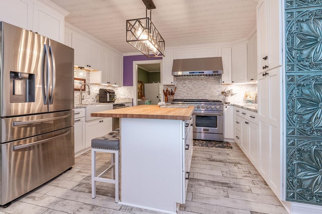 5870 Monk House Road Somerville, TN 38068 - Photo 14 of 40 a kitchen with stainless steel appliances granite countertop a refrigerator a sink dishwasher a stove with white cabinets and wooden floor