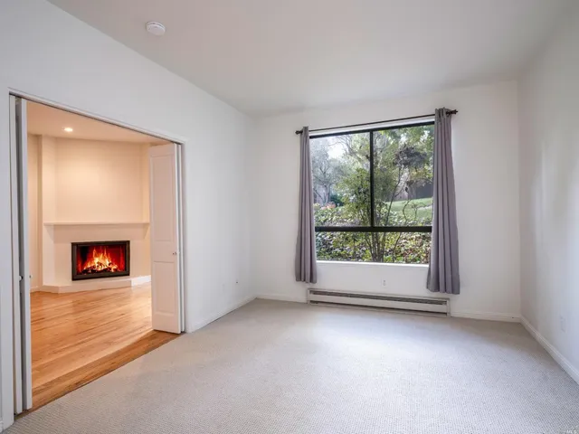an empty room with a fireplace and large window