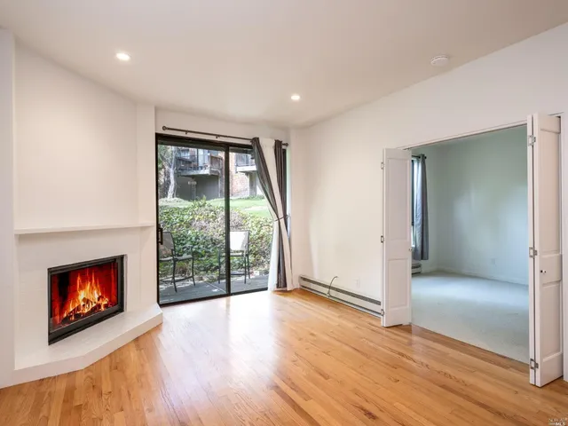 an empty room with wooden floor fireplace and windows