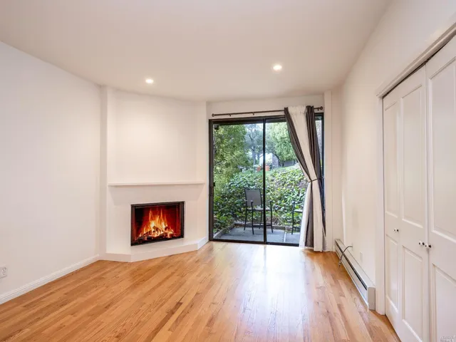 an empty room with wooden floor fireplace and windows