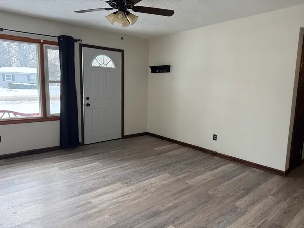 an empty room with wooden floor and windows
