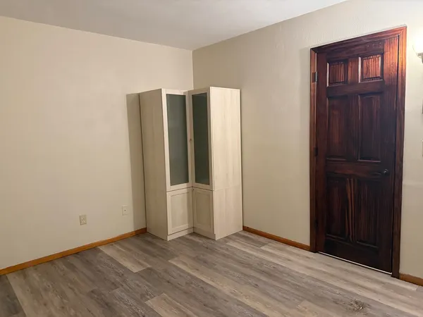 an empty room with wooden floor closet and windows