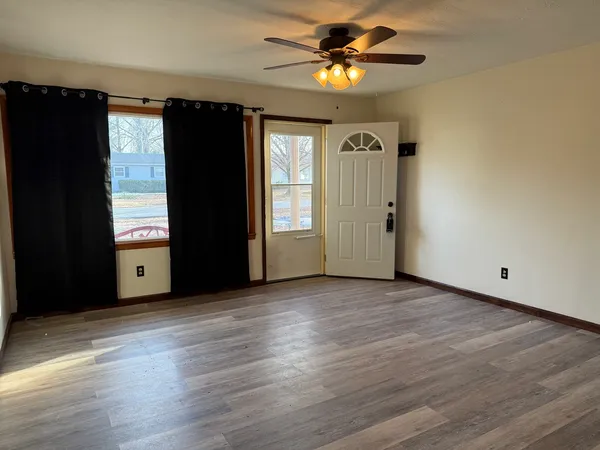 an empty room with wooden floor closet fan and windows