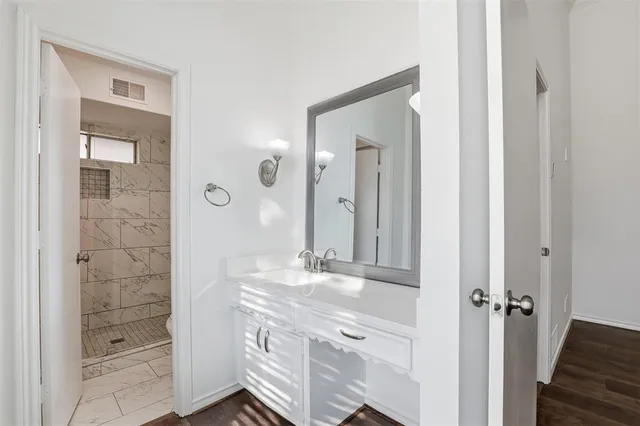 a bathroom with a granite countertop sink two mirror and shower