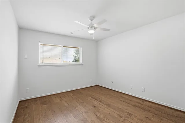 an empty room with a window and ceiling fan