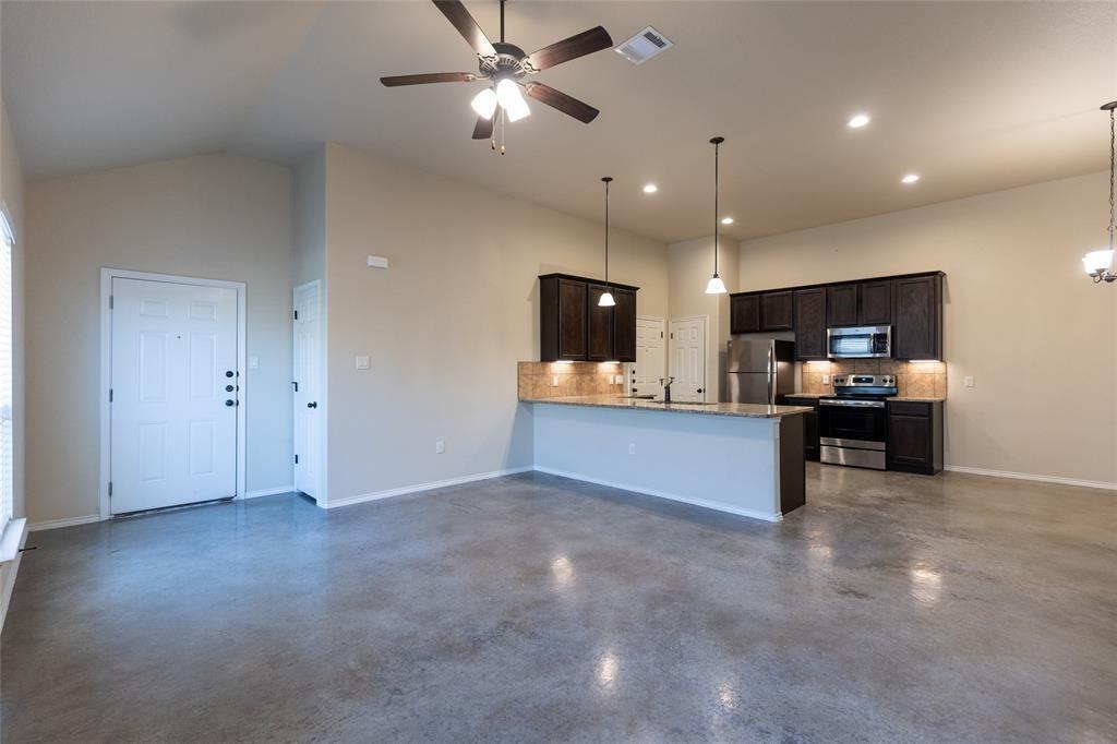 351 Joanne Loop, Unit A Buda, TX 78610 - Photo 7 of 17 An open-concept living space integrates a modern kitchen and dining area with durable concrete flooring.