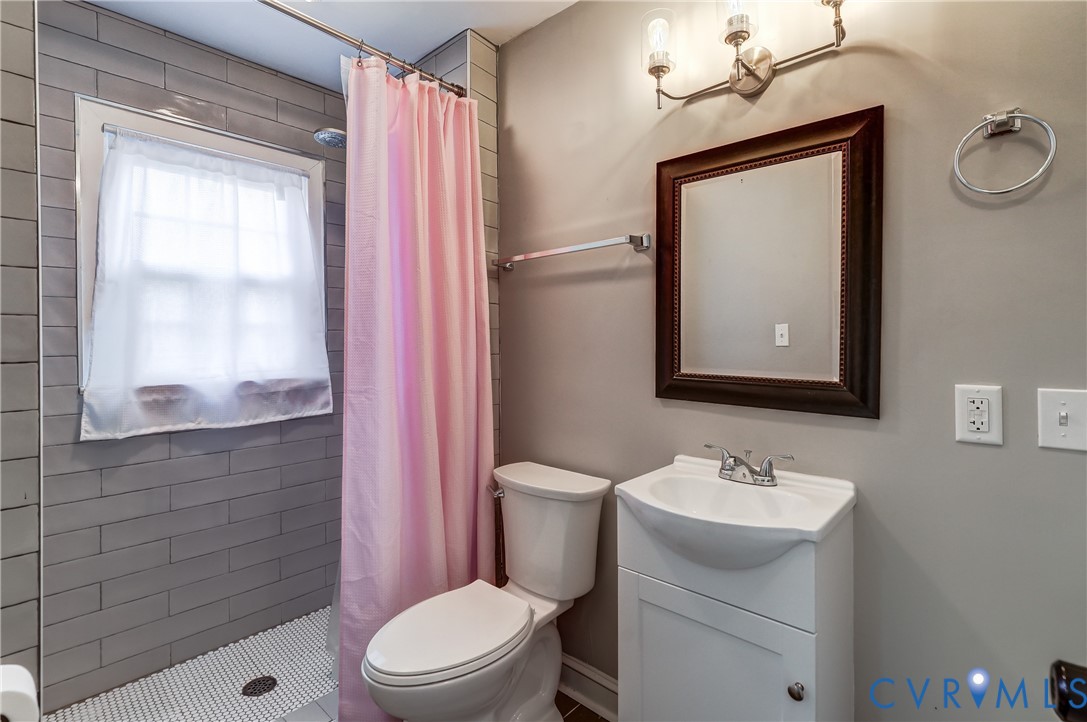 418 4th Street West Point, VA 23181 - Photo 17 of 36 a bathroom with a toilet a sink a mirror a window and vanity