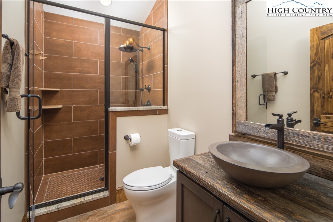 331 Goldenrod Road Boone, NC 28607 - Photo 25 of 50 a bathroom with a granite countertop sink a toilet a mirror and shower