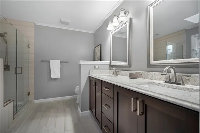 a view of a hallway with wooden floor and a bathroom