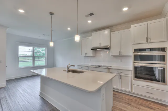 a kitchen with granite countertop a sink a counter space appliances and cabinets