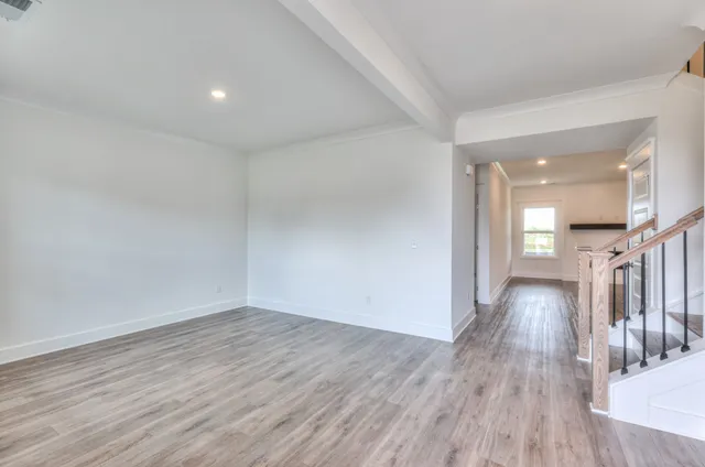 a view of an empty room with wooden floor and stairs