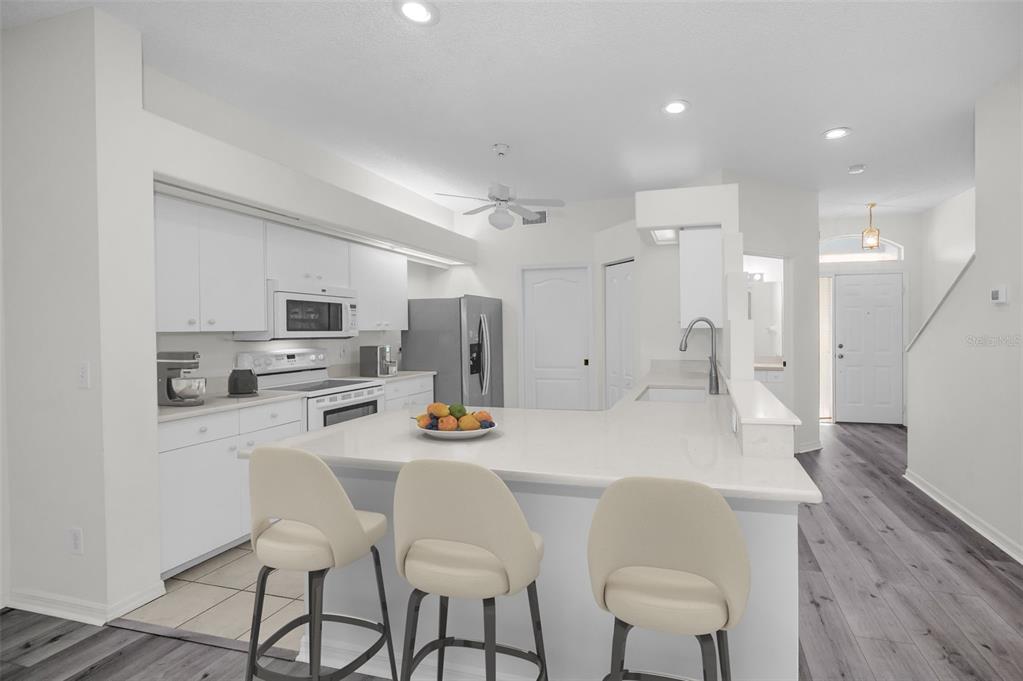 271 Hemingway Drive Oldsmar, FL 34677 - Photo 10 of 31 a kitchen with stainless steel appliances kitchen island granite countertop a dining table chairs refrigerator and microwave