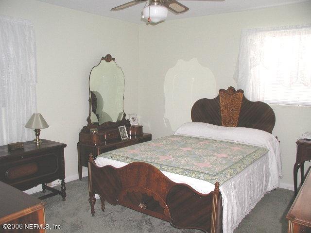2704 Sam Road Jacksonville, FL 32216 - Photo 6 of 9 a bedroom with a bed and a chandelier