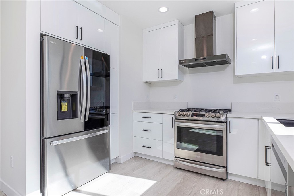 7446 Mammoth Avenue Van Nuys, CA 91405 - Photo 9 of 30 a kitchen with stainless steel appliances white cabinets and white appliances