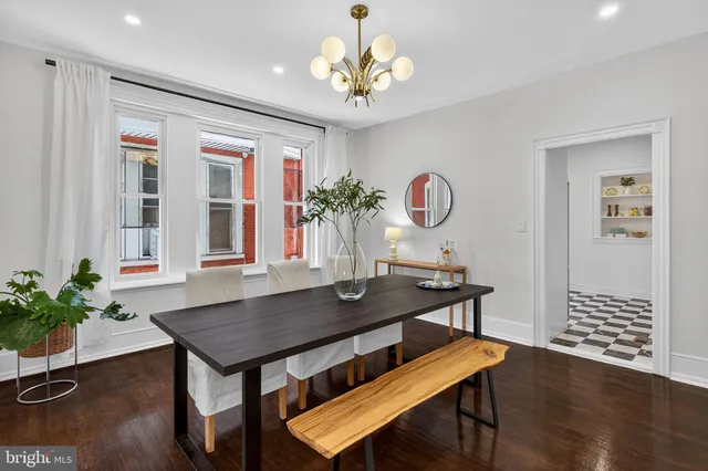 a dining room with wooden floor a chandelier a glass table and chairs