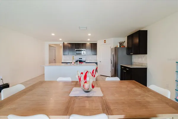 a kitchen with stainless steel appliances kitchen island granite countertop a refrigerator a stove a microwave oven a dining table and chairs with wooden floor