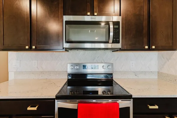 a kitchen with stainless steel appliances a sink dishwasher a stove top oven a refrigerator with wooden cabinets and floor