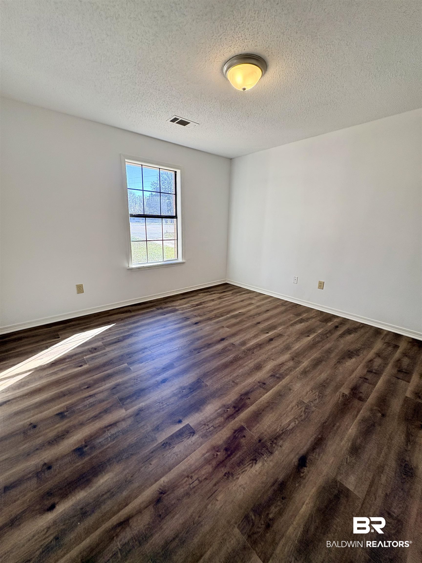 47 Fairview Street Evergreen, AL 36401 - Photo 2 of 15 Empty room with a textured ceiling and dark wood-style floors