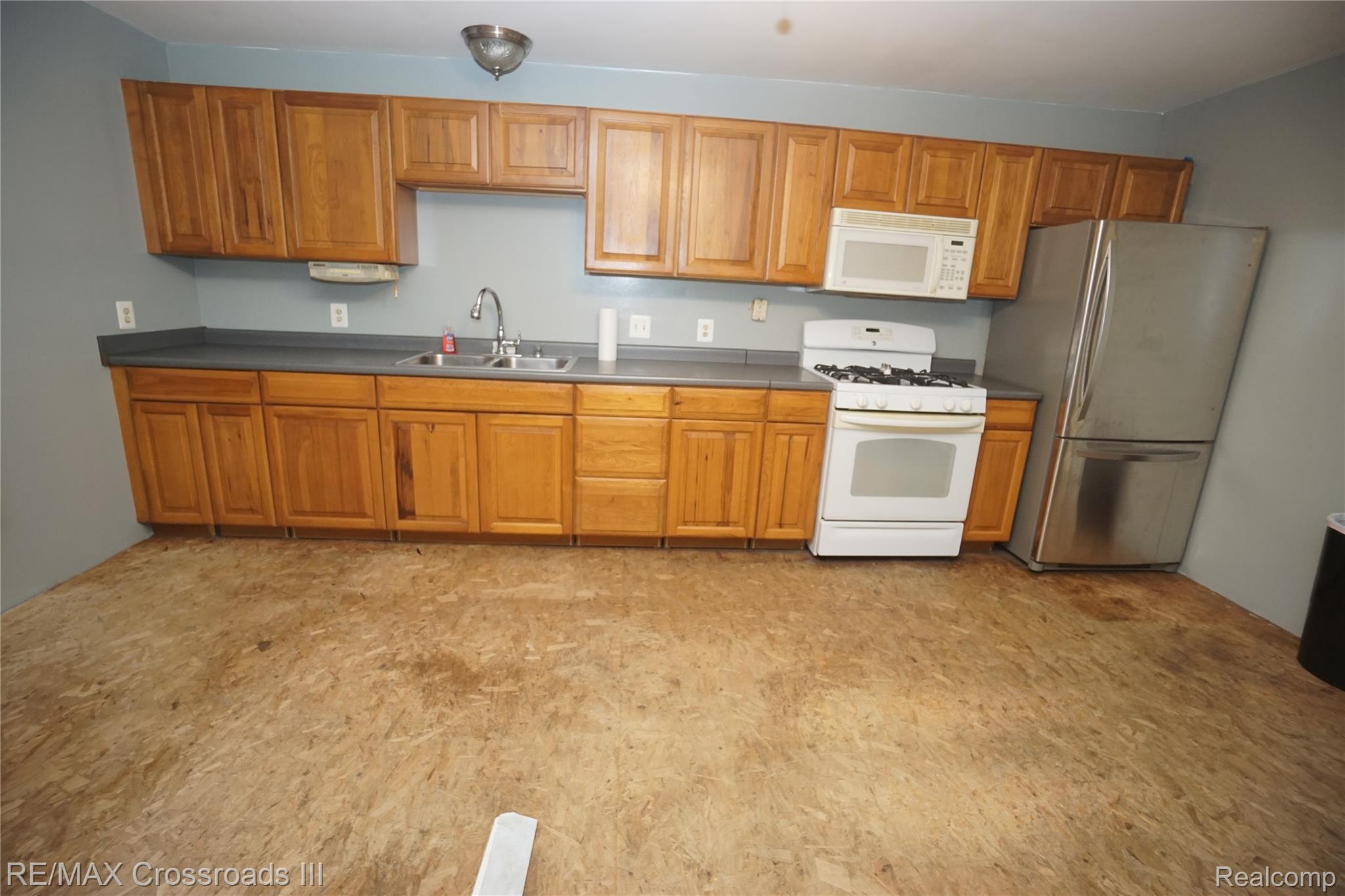 7150 Sheldon Road Belleville, MI 48111 - Photo 7 of 11 Kitchen featuring wood cabinetry, a stainless steel refrigerator, white range, white microwave, and a double basin sink