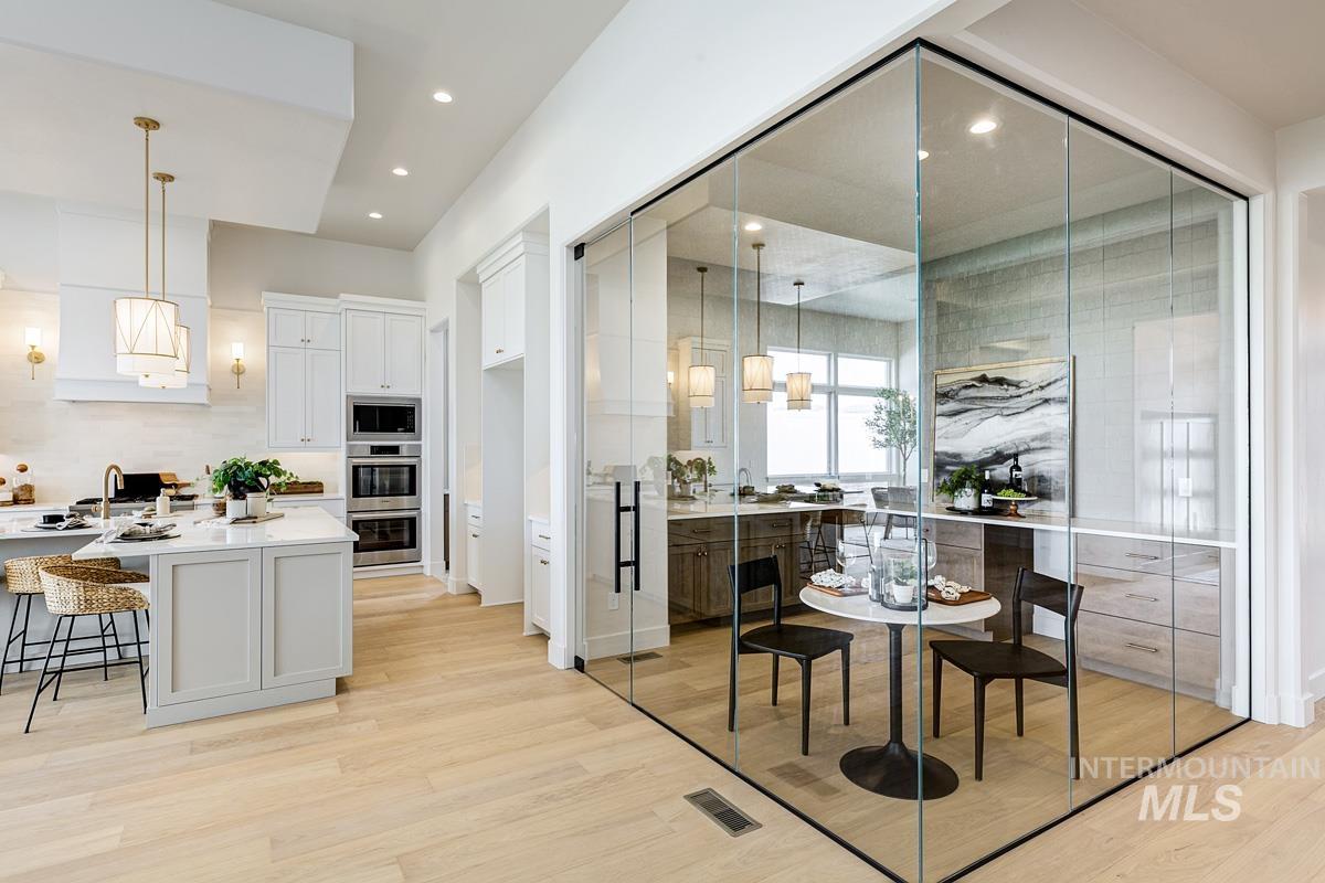13758 North Ruffed Grouse Way Boise, ID 83714 - Photo 6 of 45 Kitchen with light wood-style floors, white cabinets, a breakfast bar, decorative light fixtures, and light stone countertops