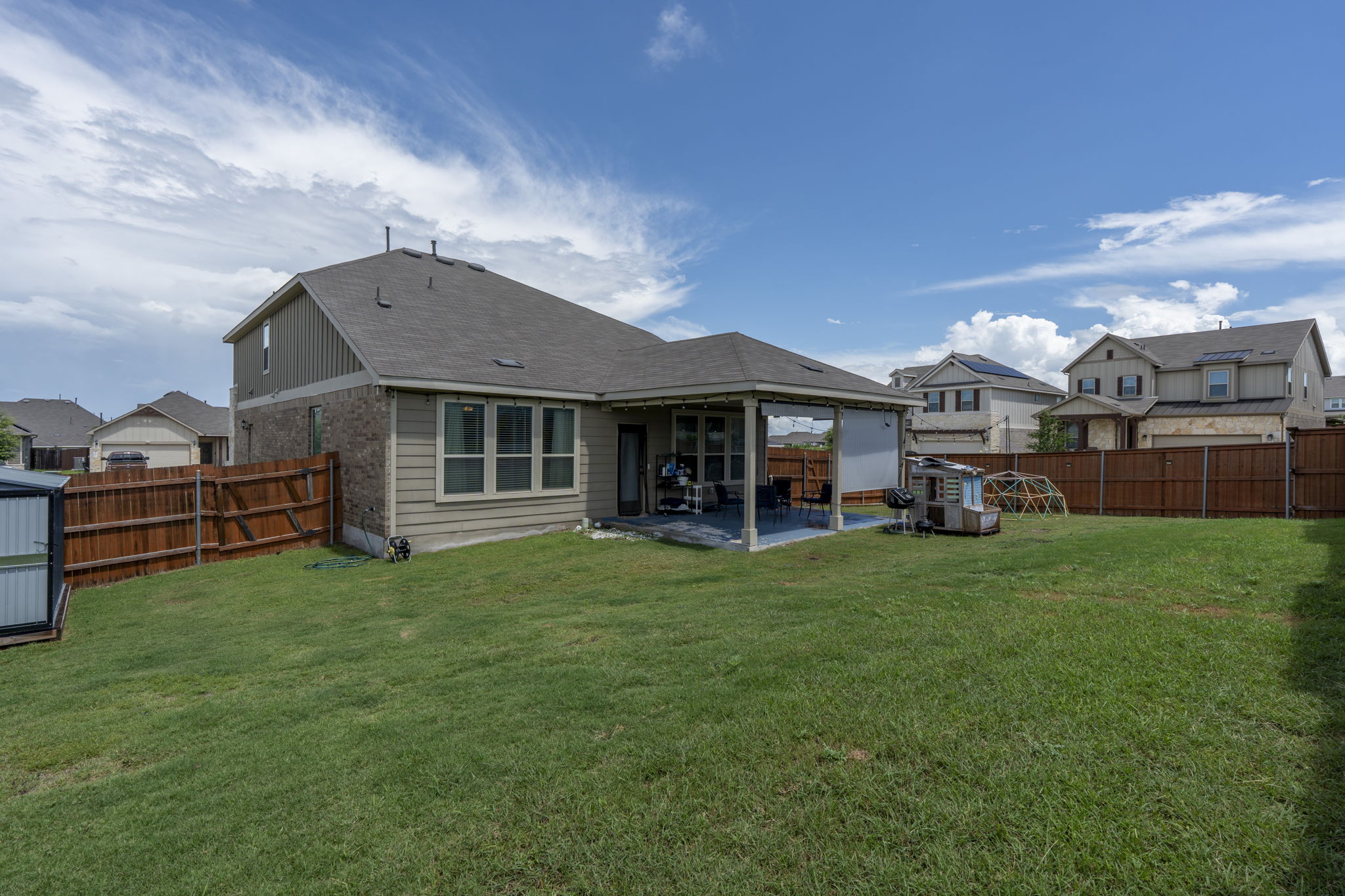 548 Purple Heart Drive Buda, TX 78610 - Photo 25 of 35 A spacious backyard with a covered patio offers outdoor living space and ample green area.