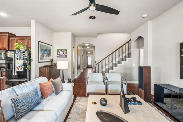 a kitchen with stainless steel appliances granite countertop a kitchen island a stove a refrigerator a sink a dining table and chairs with wooden floor