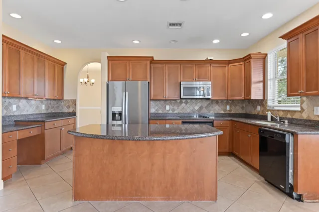 a large kitchen with stainless steel appliances granite countertop a stove a sink dishwasher and a refrigerator