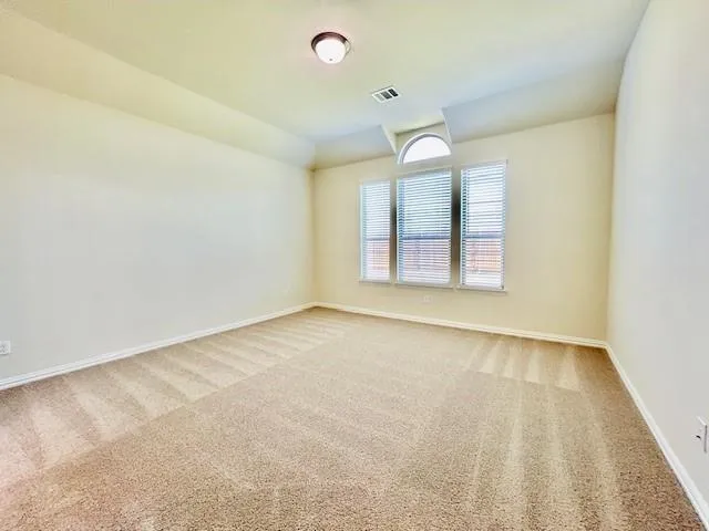 an empty room with windows and chandelier fan