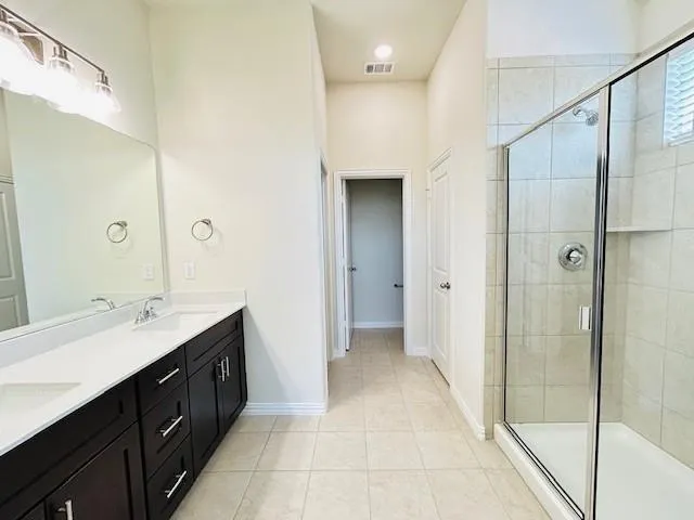 a spacious bathroom with a double vanity sink a mirror and a shower