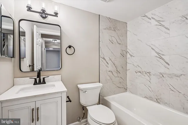 a bathroom with a toilet sink vanity tub and shower